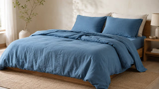 Blue linen bedding set styled on a wooden bed in a bright bedroom