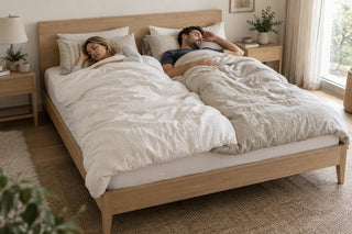 Couple sleeping under two separate duvets on one shared king bed.